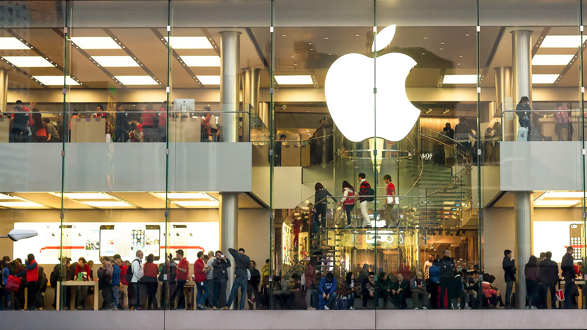 A group of people are standing in front of an apple store.