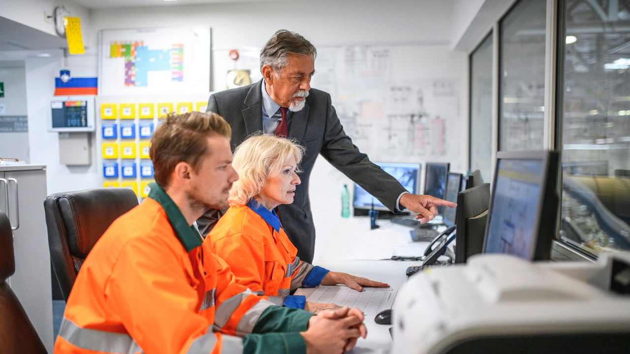 A group of people working at a computer in a factory.