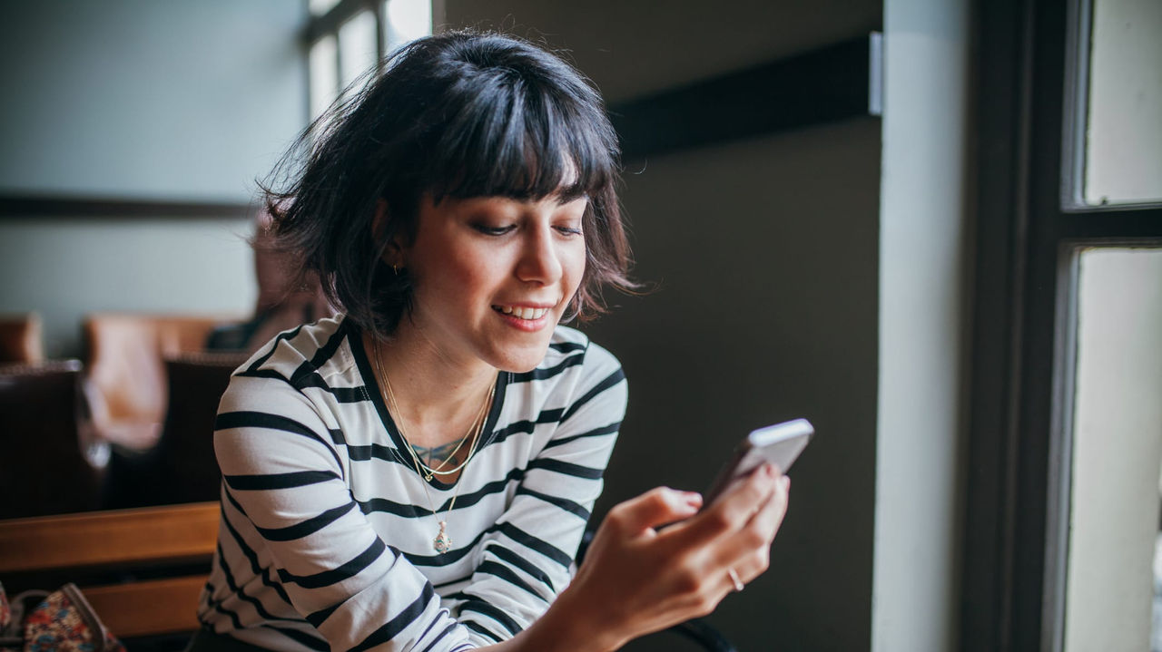 A woman sitting on a bench looking at her phone.