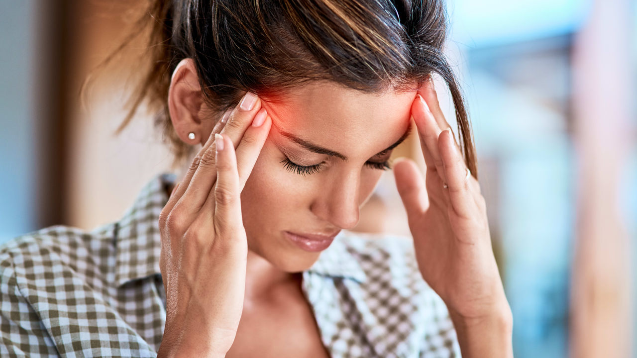 A woman is holding her head with her hands.