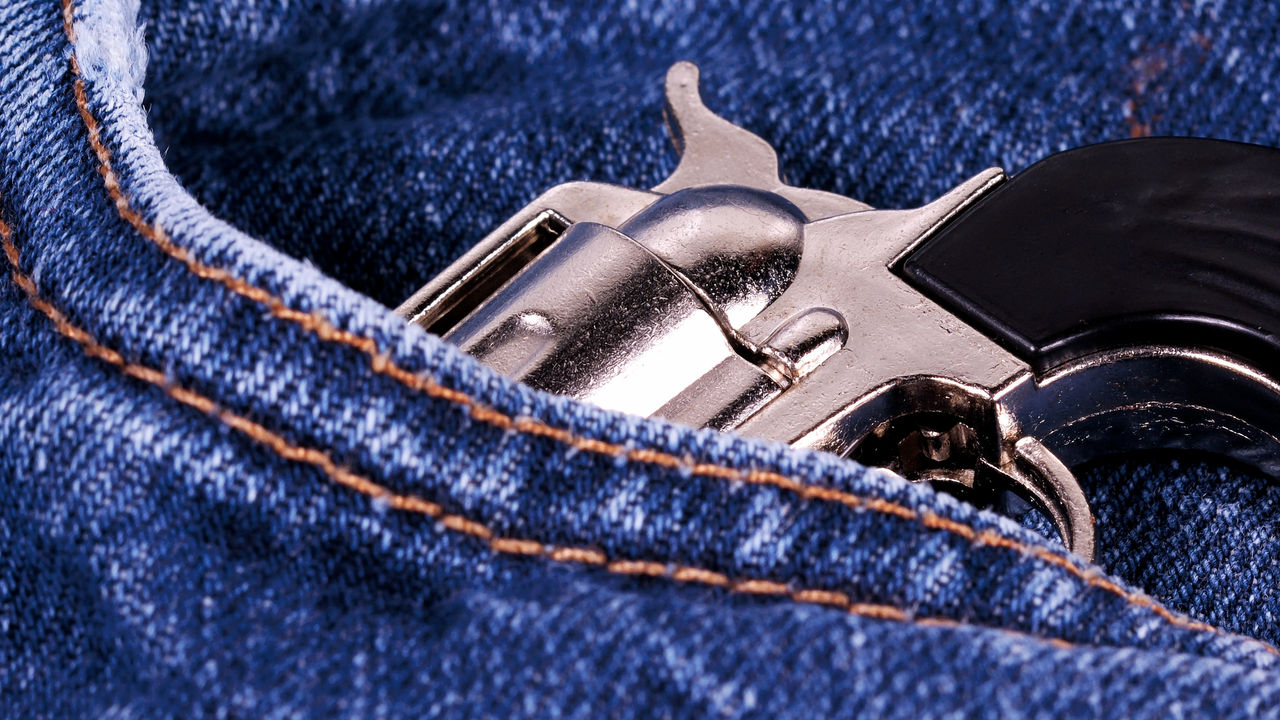 A revolver is in the pocket of a pair of blue jeans.