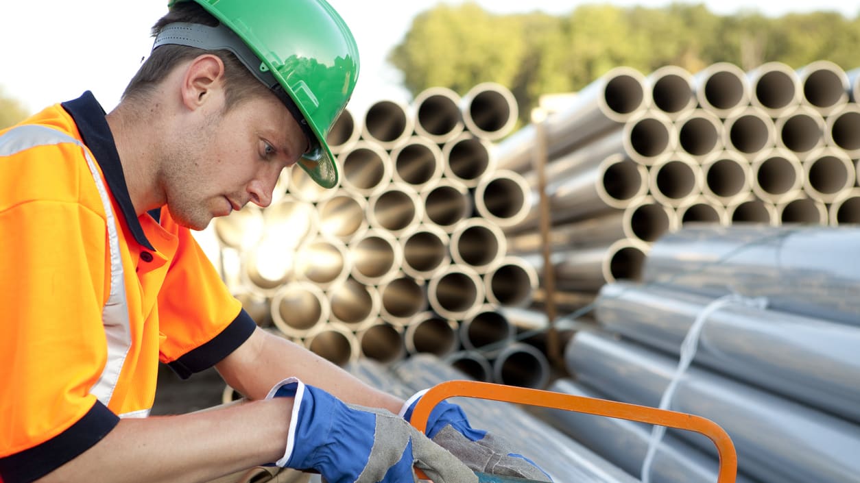 A construction worker is working on a pipe.