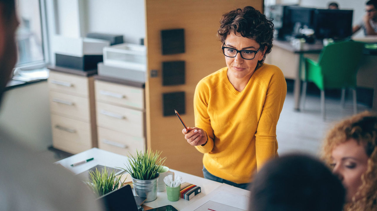 A woman is giving a presentation to a group of people in an office.