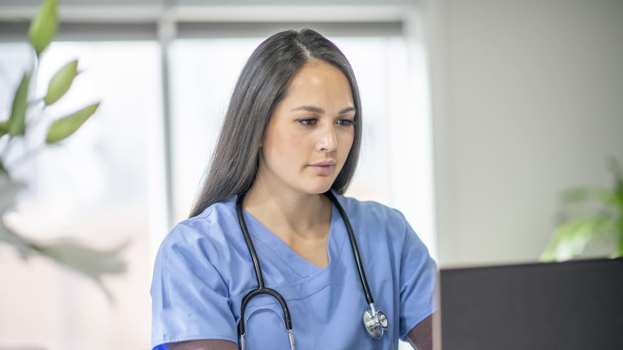 A female nurse working on a laptop computer.