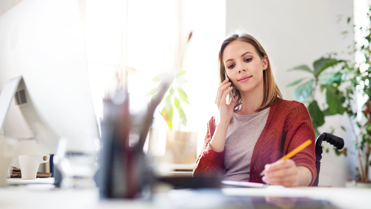 A woman talking on the phone while sitting at her desk.