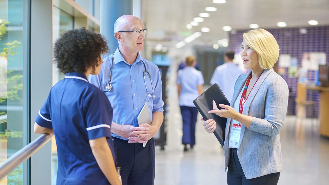 Two nurses talking to each other in a hallway.