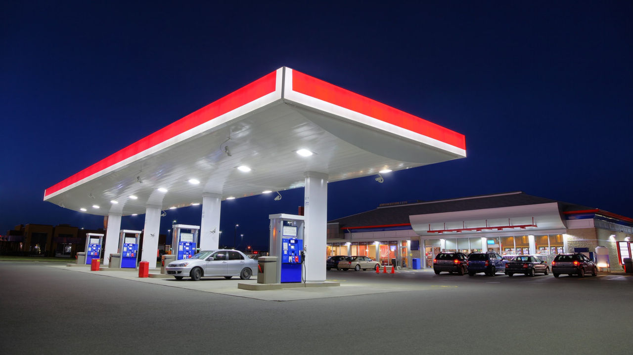 A gas station at night with cars parked in front of it.