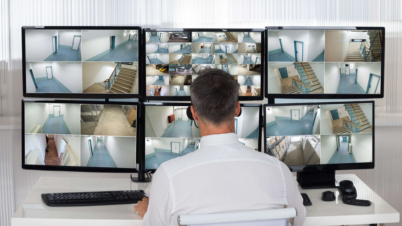 A man sitting at a desk with several monitors.