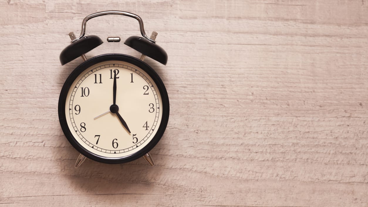 A black alarm clock on a wooden surface.