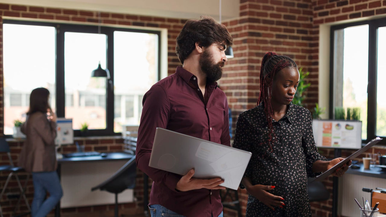 A group of people in an office looking at a laptop.