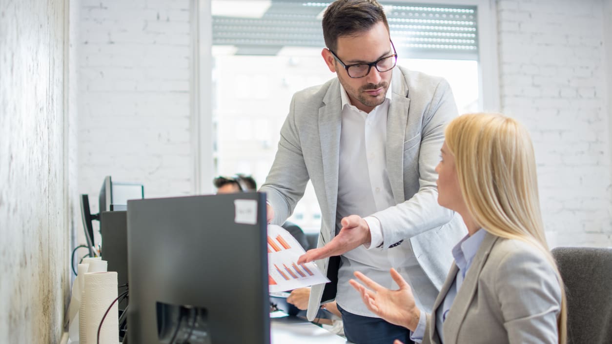 A man and woman in an office talking to each other.