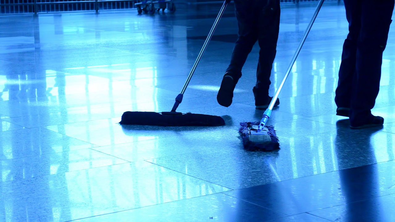 Two people mopping the floor of an airport.