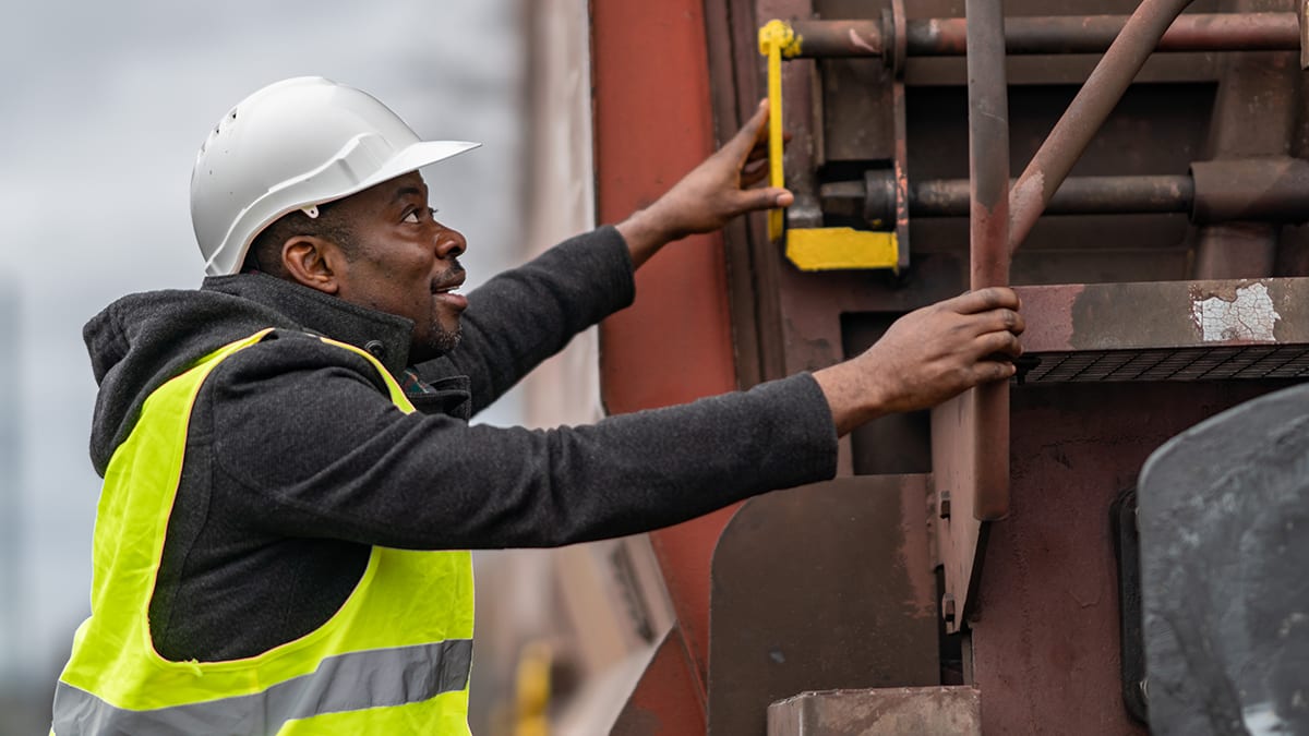 A man in a hard hat is working on a train.