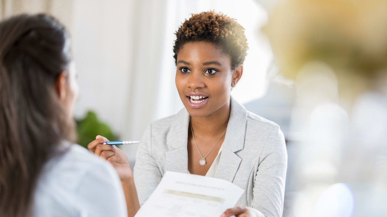 A woman is talking to another woman in an office.