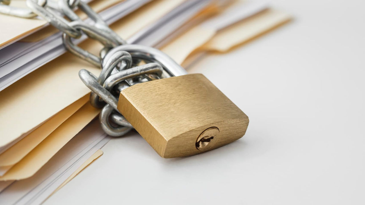 A padlock is attached to a stack of papers.