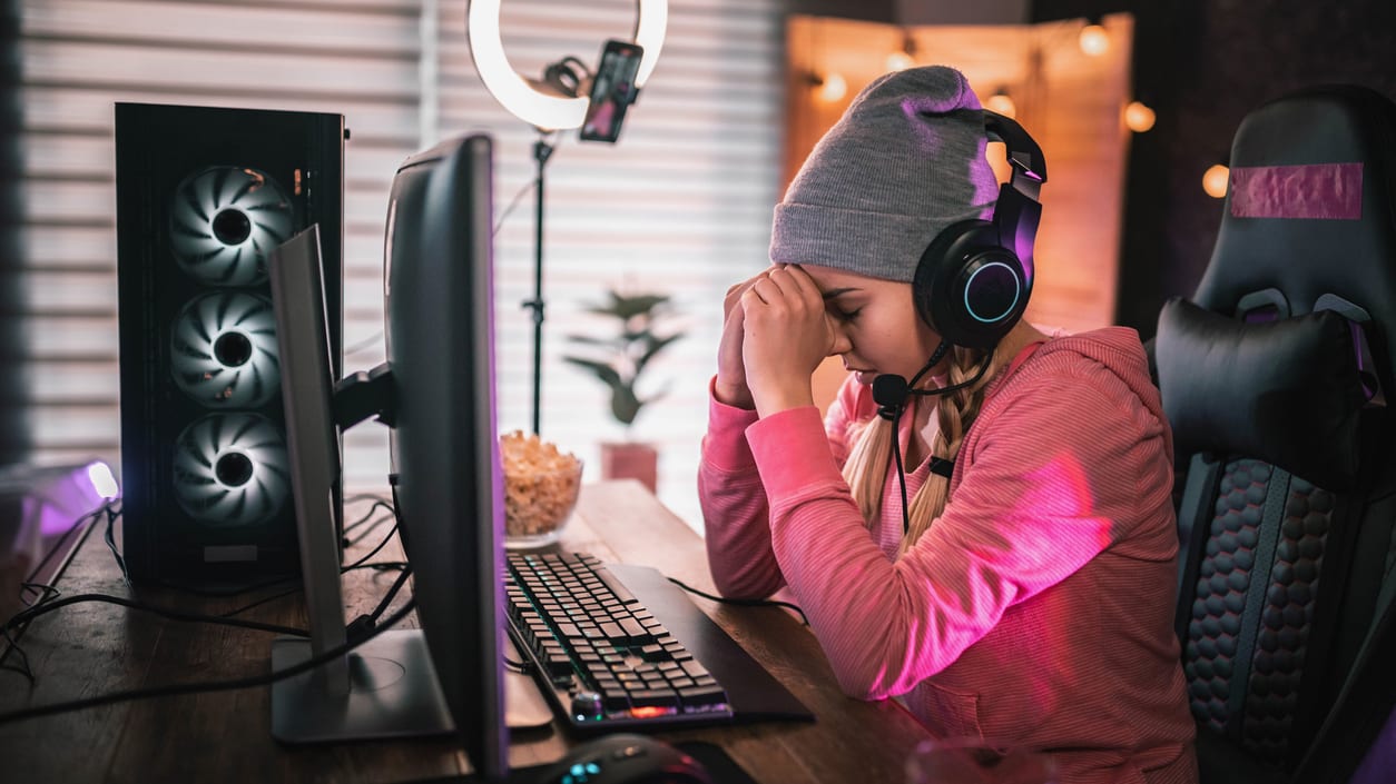 A girl sitting at a computer with headphones on.