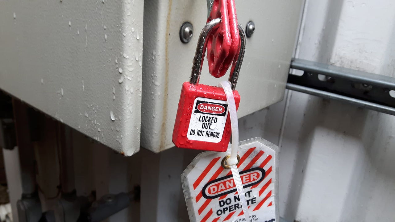 A red padlock is attached to a metal door.