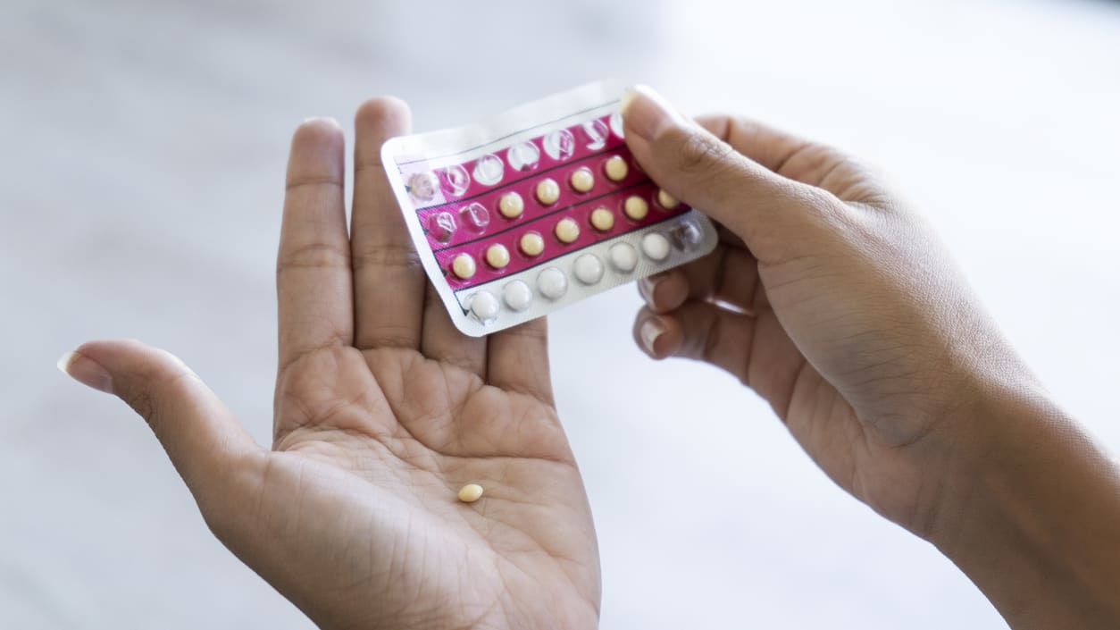 A woman's hand holding a pack of pills.