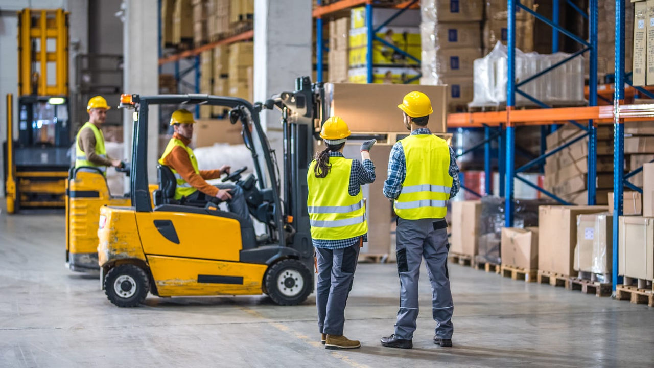 Three forklift drivers working in a warehouse.