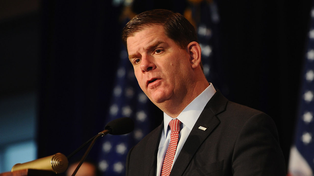 A man in a suit and tie speaking into a microphone.