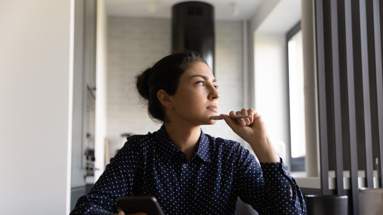 A woman is looking at her phone while sitting at a table.