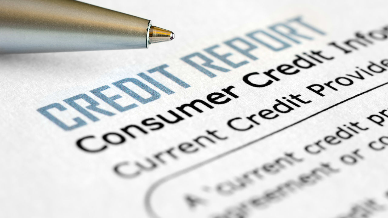 A pen sits on top of a credit report.