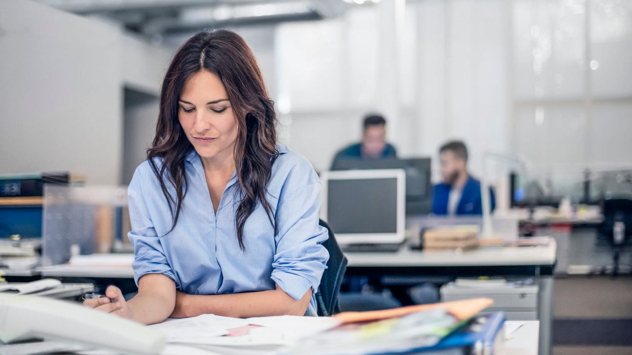 A woman working in an office with other people.