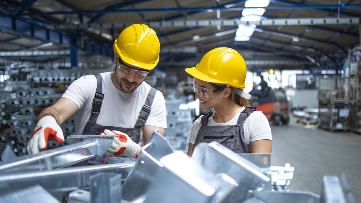 Two workers in hard hats working in a factory.