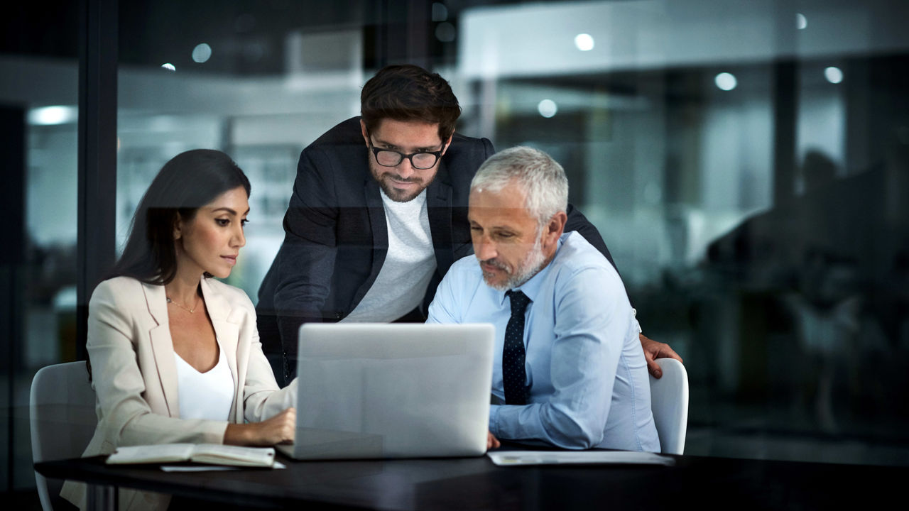 Three business people looking at a laptop.