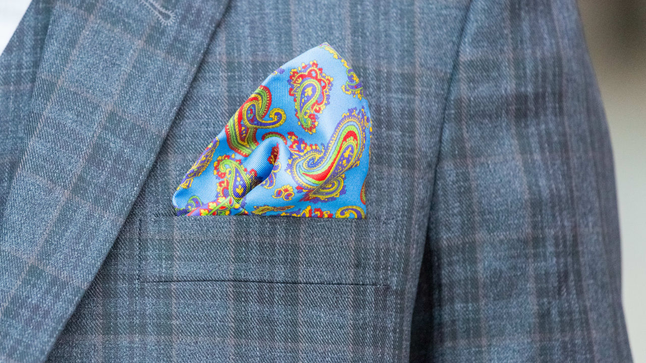 A man in a suit with a paisley pocket square.