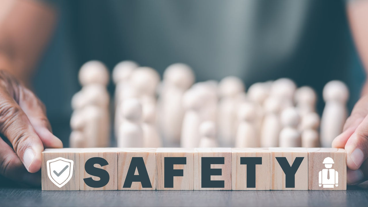 A person holding a wooden block with the word safety on it.