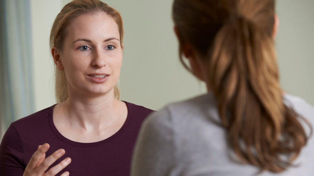 A woman talking to another woman in a room.