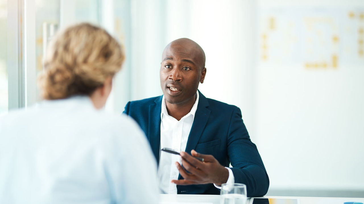 Two business people talking at a table in an office.