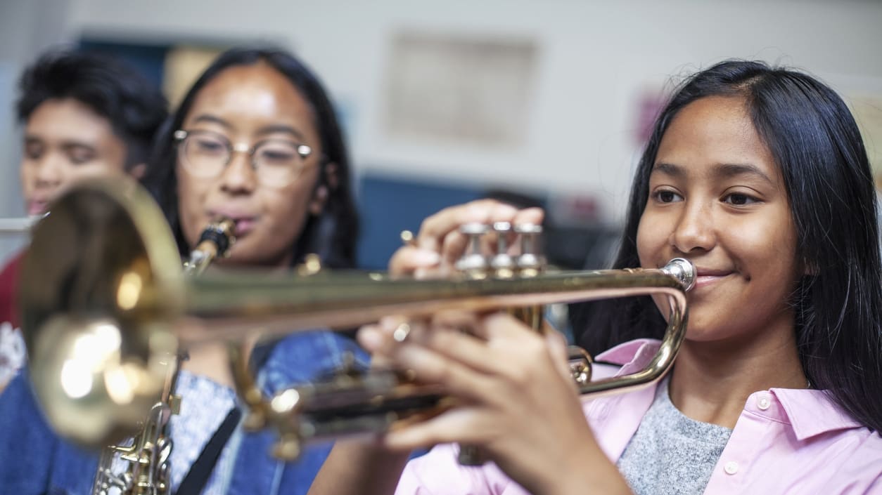 Two girls playing the trumpet in a classroom.