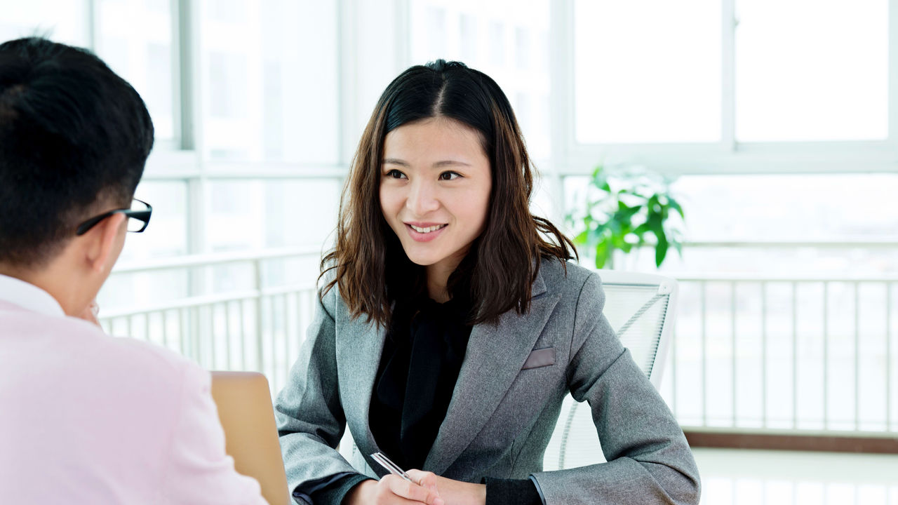 A man and woman talking at a desk in an office.
