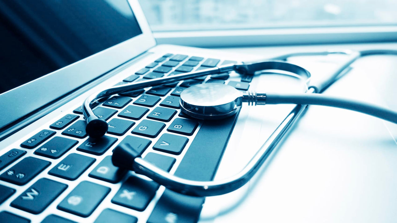 A stethoscope sits on top of a laptop computer.