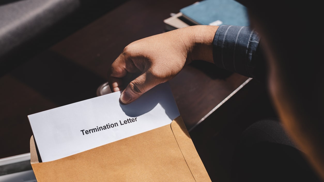 A person holding a paper with the word termination letter on it.