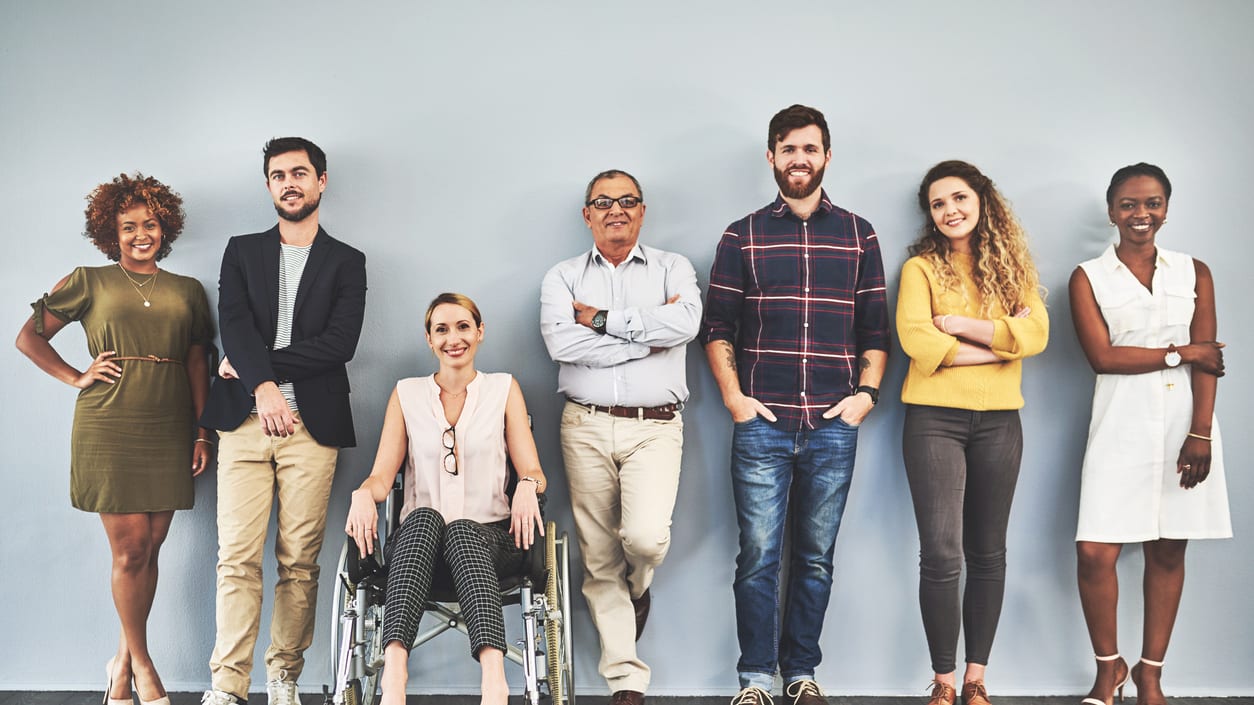 A group of people standing in front of a gray wall.