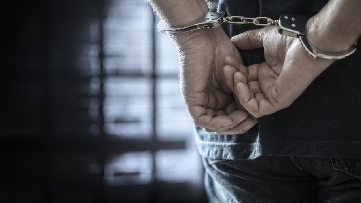 A man in handcuffs holding his hands.