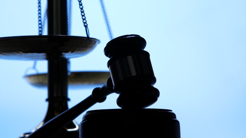 A judge's gavel on top of a scale.