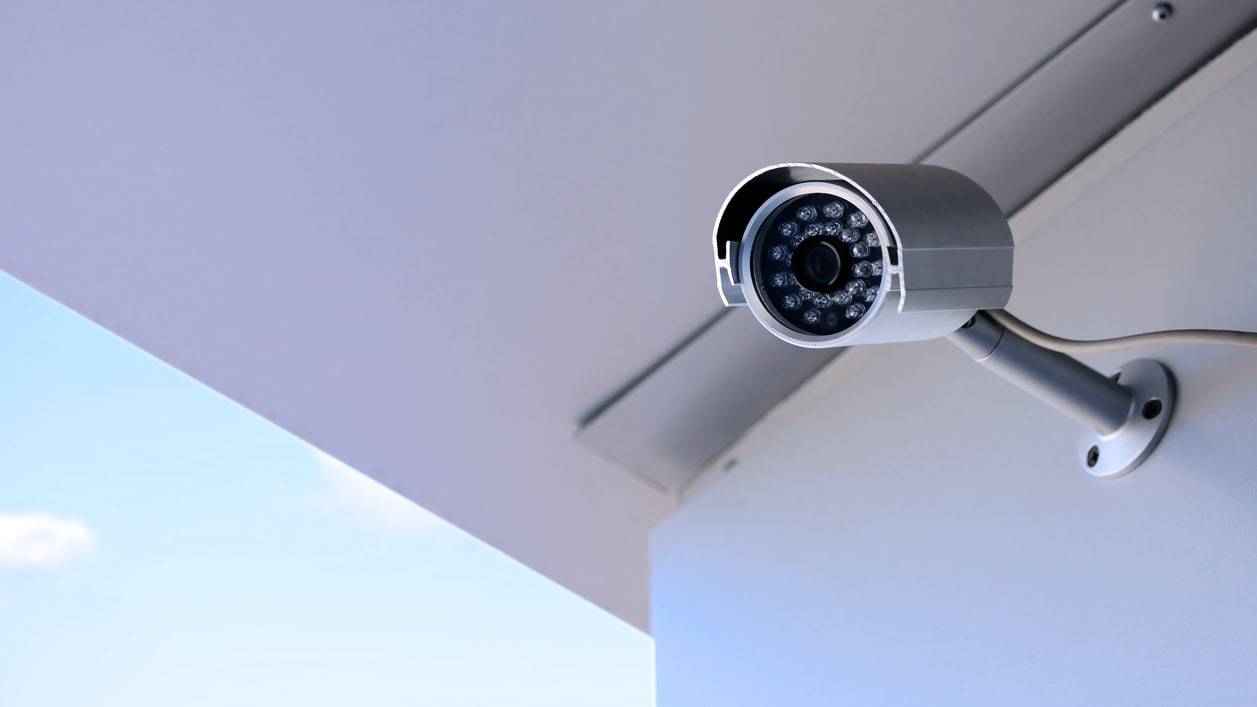 A cctv camera is mounted on the side of a building.