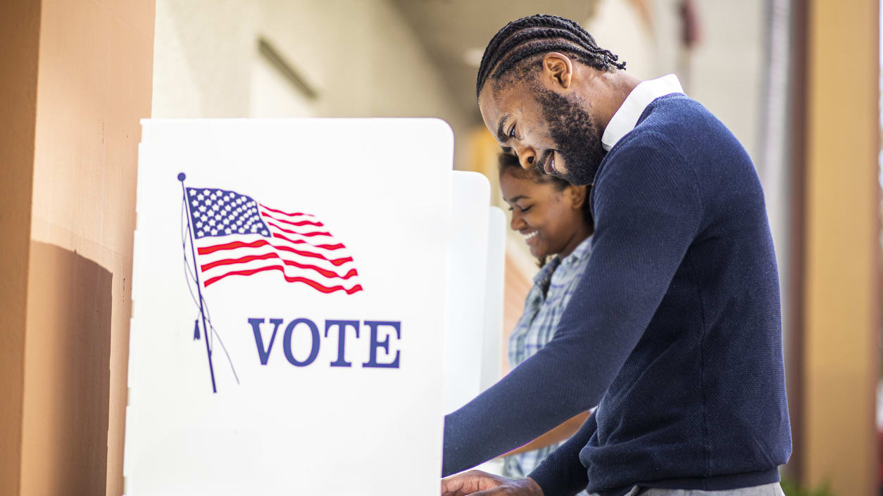 A man and woman voting in a voting booth.