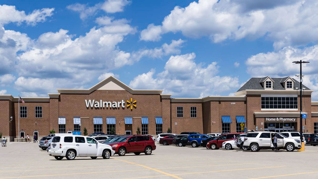 A view of a walmart store with cars parked in front of it.