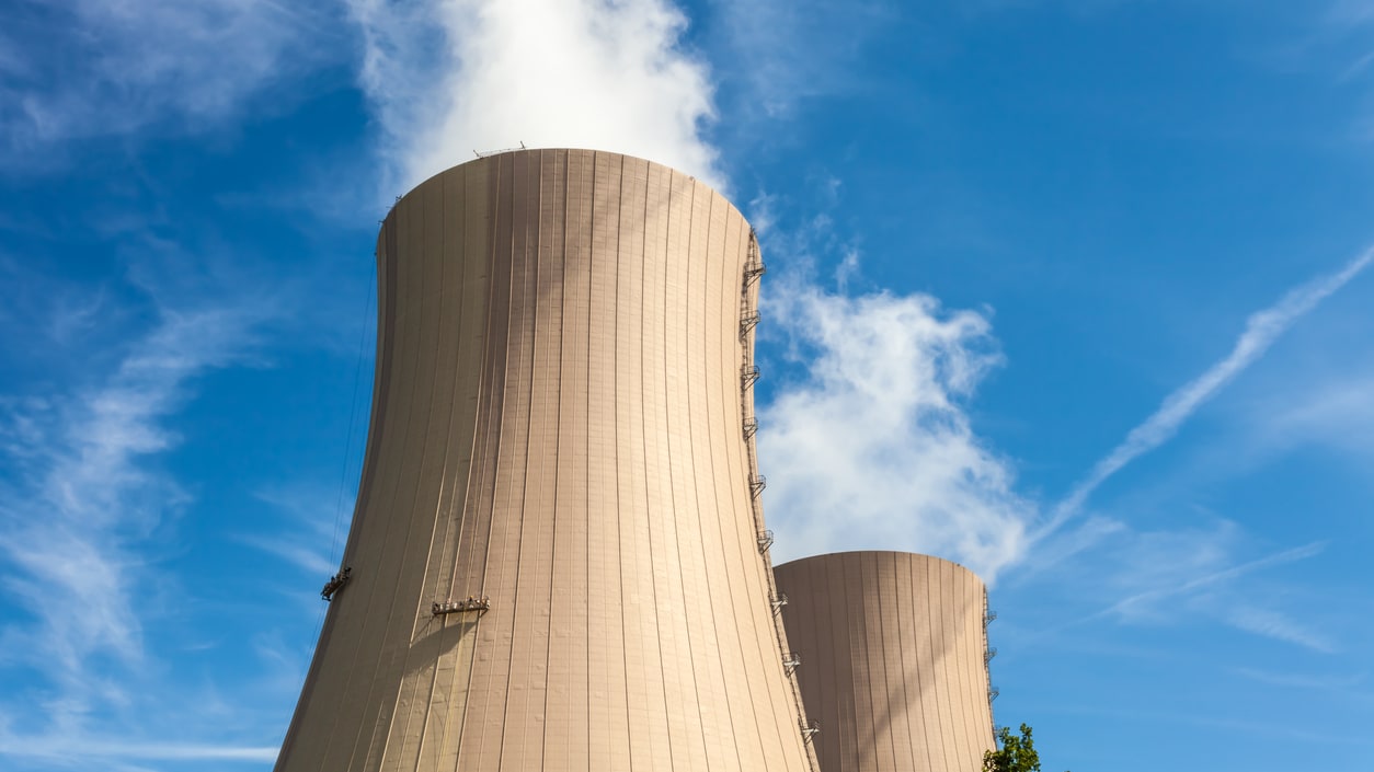 Two cooling towers with smoke coming out of them.