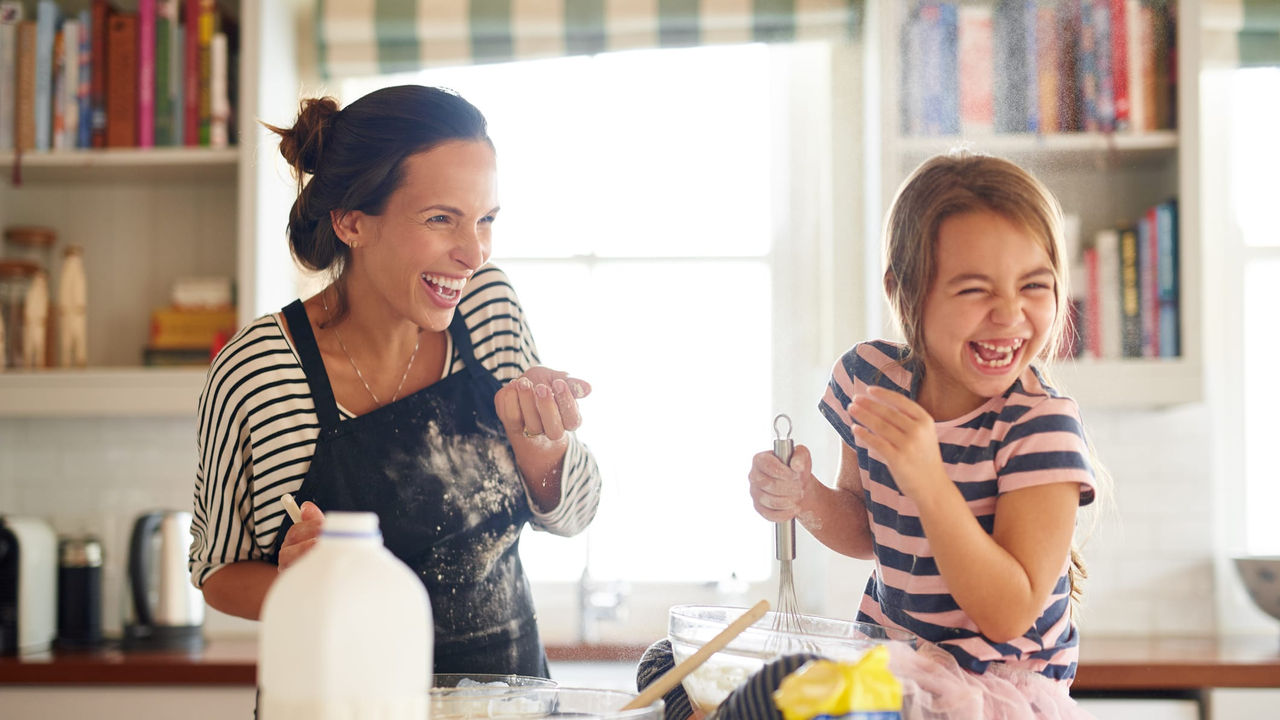 A mother and daughter are making cookies in the kitchen.