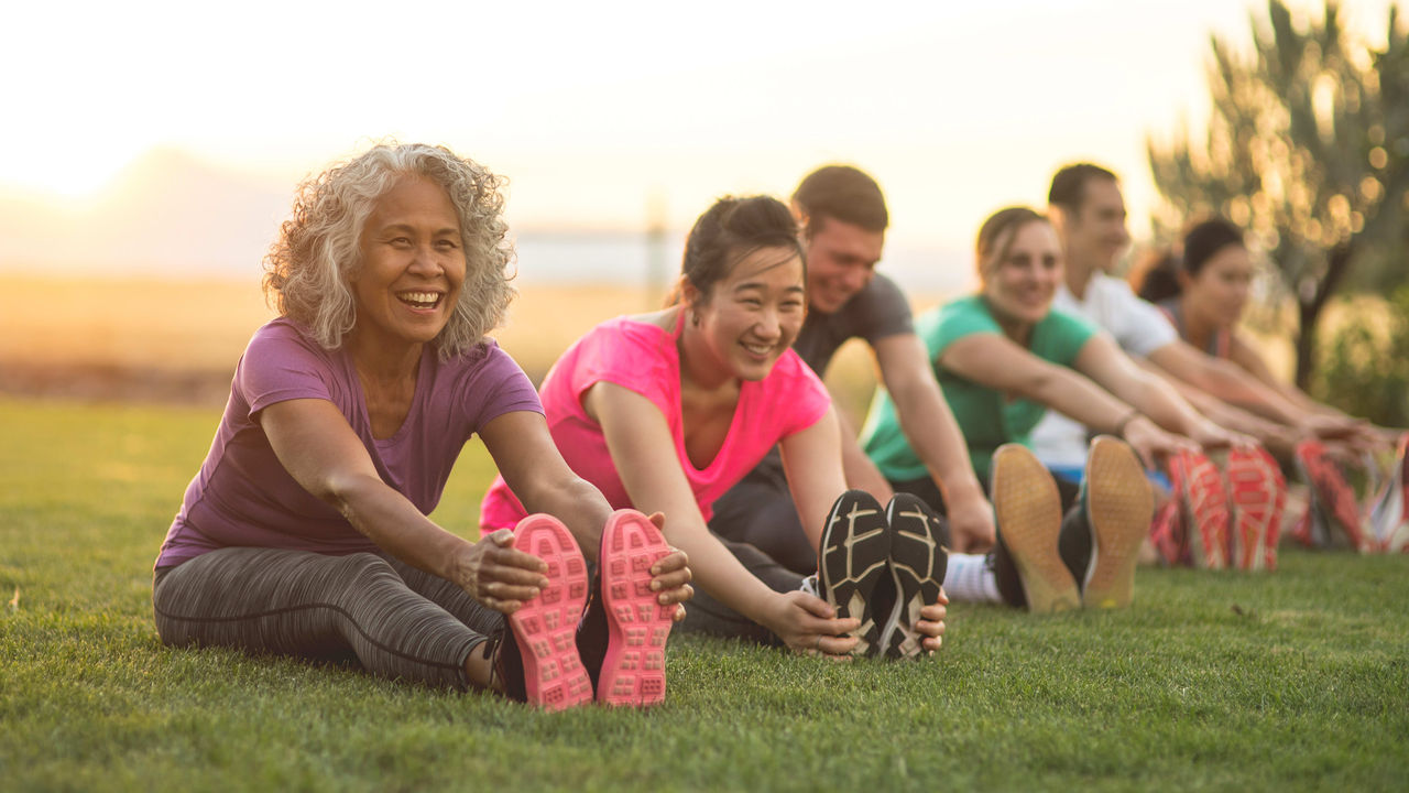 A group of people stretching in the grass.