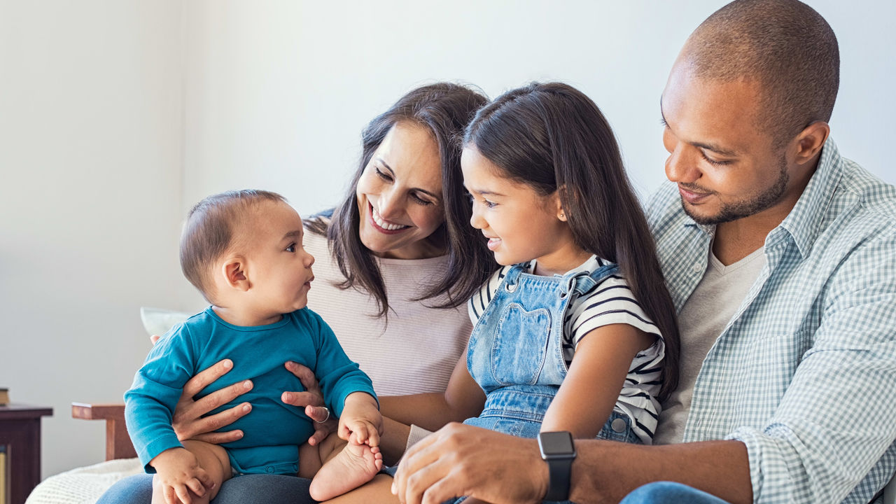 A family is sitting on a couch with a baby.