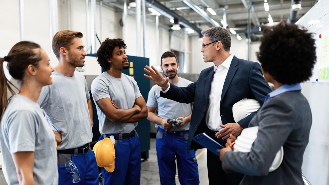 A group of people in hard hats talking to each other in a factory.