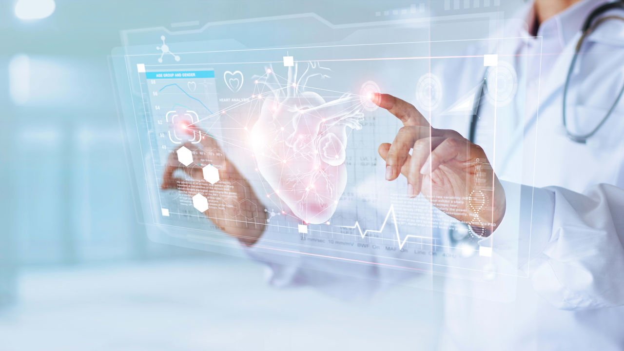A doctor is pointing at a screen with a heart on it.