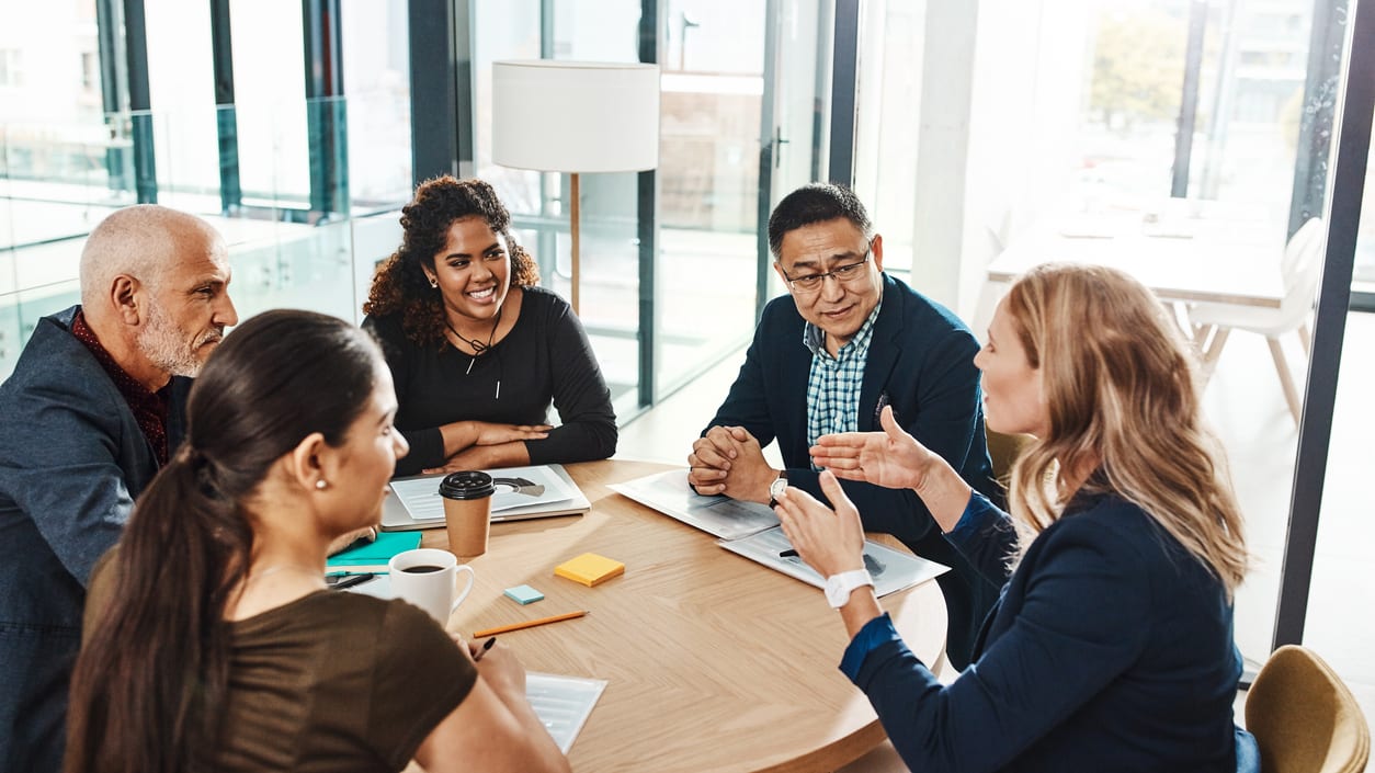 A group of people sitting around a table in an office.